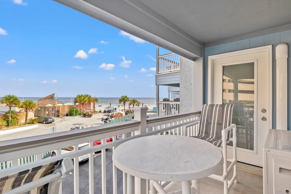 Balcony seating overlooking the ocean, framed by palm trees. The tranquil setting invites guests to enjoy morning coffee, watch the sunset, or simply relax with a book while soaking in the coastal ambiance.