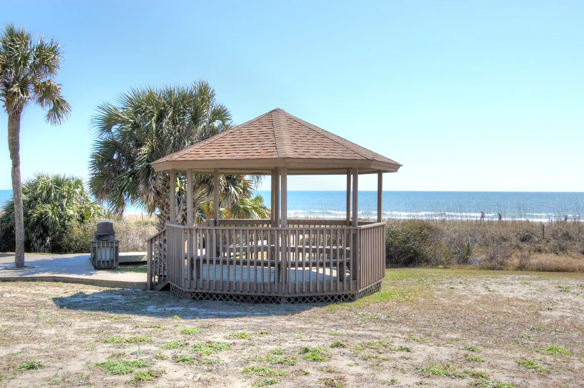 A charming oceanfront gazebo surrounded by palm trees and a sweeping view of the Atlantic. The gazebo provides a cozy spot to relax, enjoy the view, or have a small gathering, with the calm sea in the background.